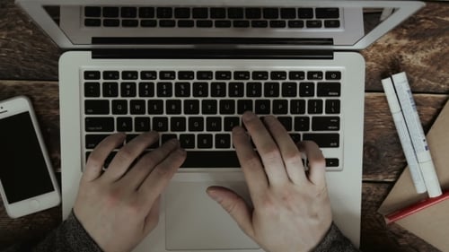 Hands Typing on Laptop on Wooden Table