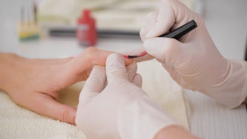 Manicurist Applying Red Nail Polish to Fingernails
