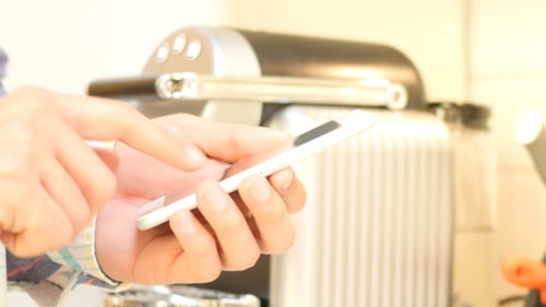Hand Using Smartphone by Coffee Machine
