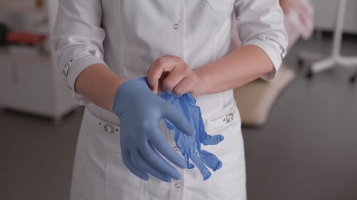 Medical Professional Puts On Surgical Gloves in Clinic