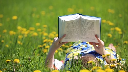 Woman Reading Book on Grassy Dandelion Field