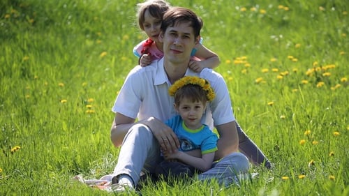 Father Relaxing with Children on Spring Meadow