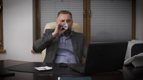 Chief In His Office Working With a Laptop And Drinking Coffee