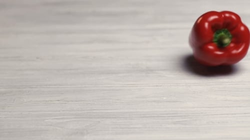Red Bell Pepper Rolling on a Wooden Surface