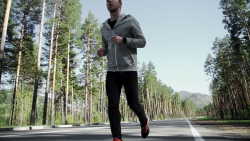 Man Running Toward Camera on Forest Road