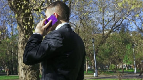 Man in Suit Talking on Phone in Park