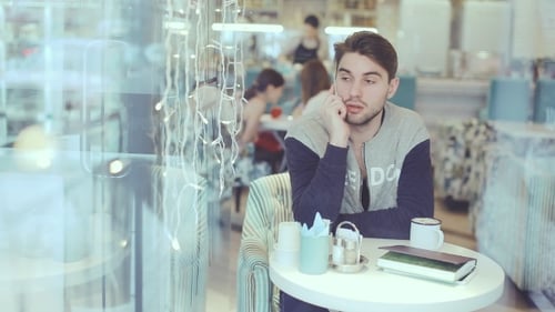 Young Man Talking On Cell Phone In Cafe