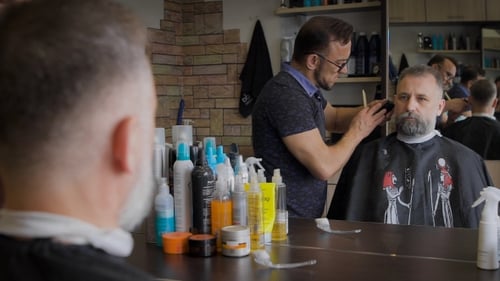 Barber Trimming Beard with Scissors at Shop