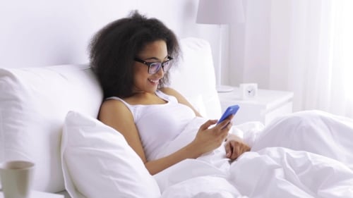 Woman Relaxing in Bed Using Smartphone
