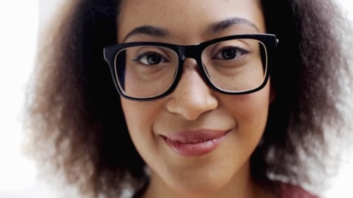 Smiling Woman with Curly Hair and Glasses Close-up