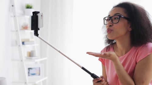 Woman Poses for Selfie Using Phone on Stick