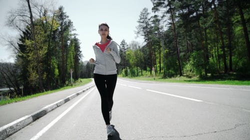 Athletic Woman Jogging on Road Near Forest