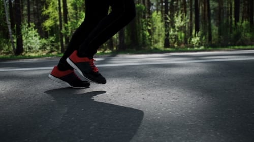 Legs of Athlete Running in Forest Setting
