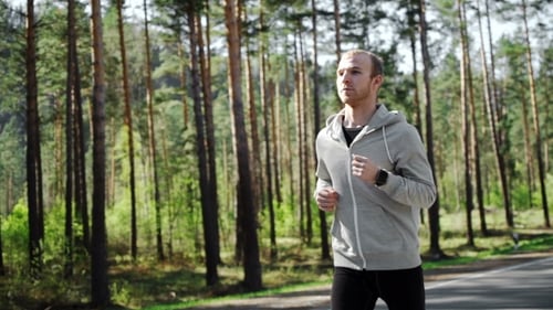 Man Running Looking At His Pulse Outside In Nature On Road With Smartwatch.