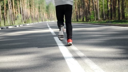 Person Running on Road Through Rural Pine Forest