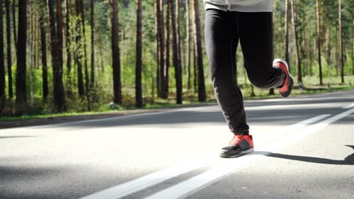 Person Running on Paved Road in Forest
