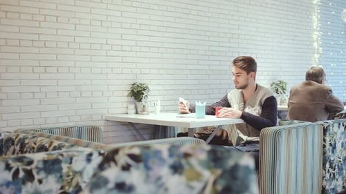 Young Man With Smartphone Sitting In Cafe,