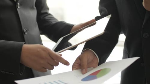 Businessmen Consult Data on Tablet and Pie Chart