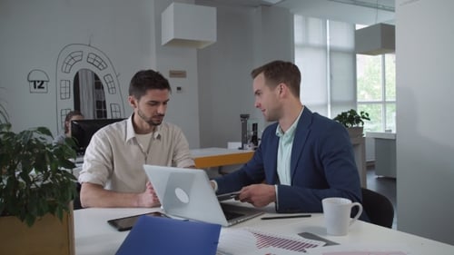 Coworkers Look On The Diagram And Discuss In The Modern Office.