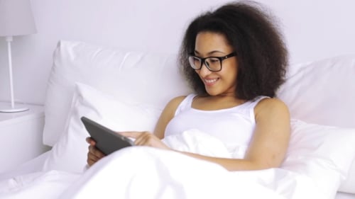 Woman Relaxes in Bed Using a Tablet
