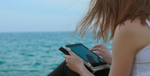 Woman Using Tablet on Beach by the Ocean