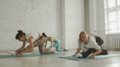 Women Stretching Legs During Yoga Class