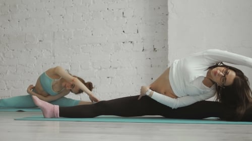 Women Practicing Splits and Stretching in Yoga Studio