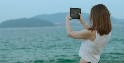 Woman on Beach Using Tablet to Take Pictures