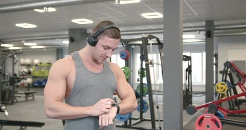 Muscular Man Checks Smartwatch at the Gym