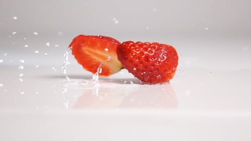 Geschnittene Erdbeeren fallen auf weiße Oberfläche