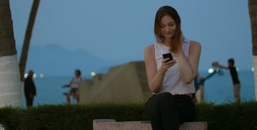 Auburn Haired Woman Uses Phone by Ocean