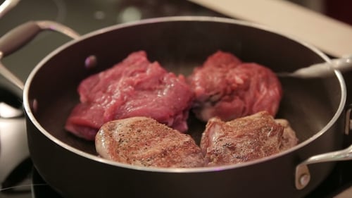 Delicious Steak Sizzling in a Pan on Stove