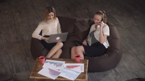 Two Young Adults Working on a Couch in Office