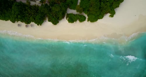 Beautiful fly over tourism shot of a sandy white paradise beach and aqua turquoise water background