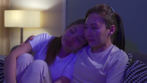 4K азиатские подруги-миллениалы смотрят телевизионную драму вместе в гостиной дома.