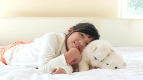 Happy Girl Cuddling with Fluffy White Puppies on Bed