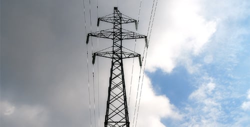 Electrical Transmission Tower Against Blue Sky with Clouds