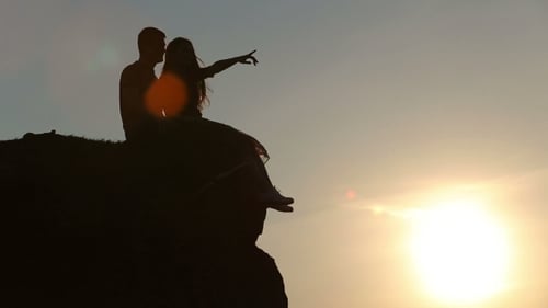 Couple Silhouetted on Cliff at Scenic Sunset