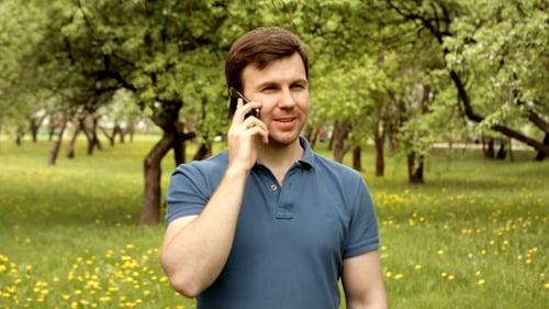 Young Man Talking on Phone in Sunny Park