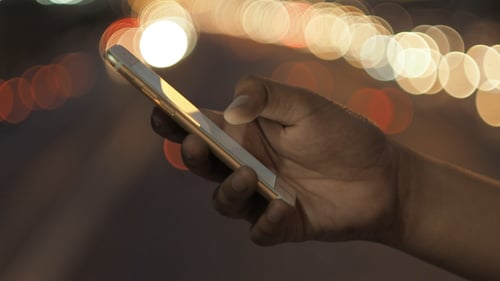 Hand Using Mobile Phone at Night with Bokeh