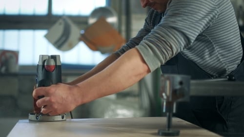 Woodworker uses milling machine in industrial setting