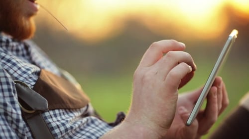 Adult With Tablet Relaxing in Park at Sunset