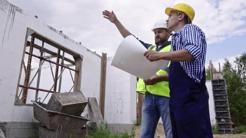 Construction Workers Inspecting Blueprints at Construction Site