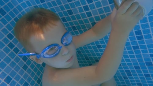 Boy In Goggles Holding Breath In Swimming Pool