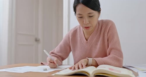 Woman Studying at Home with Book and Papers