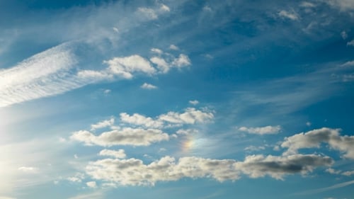 Clip von weißen, flauschigen Wolken über blauem Himmel. Wunderschöne Wolkenlandschaft mit Regenbogen