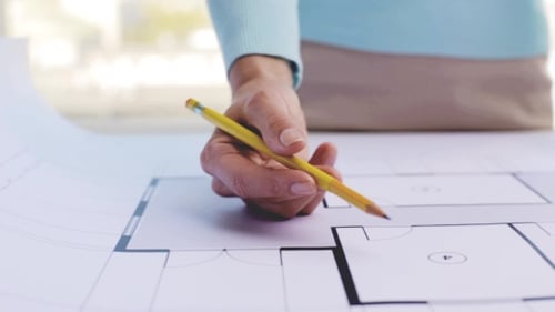 Hand gestures over architectural plans with a pencil