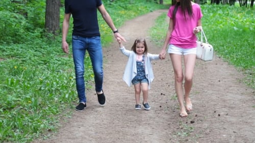 Mom And Young Daughter And Dad, a Young Family On a Walk In The Park In Summer