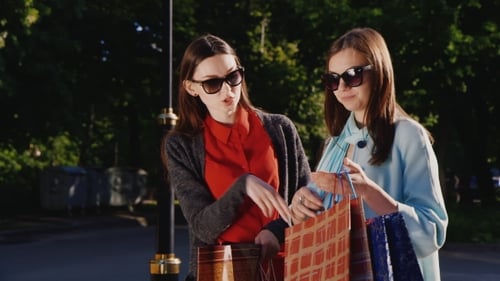 Stylish Women Admiring Purchases Outdoors