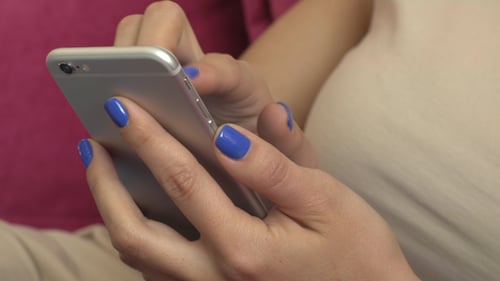 Woman Using Mobile Phone with Blue Manicured Nails